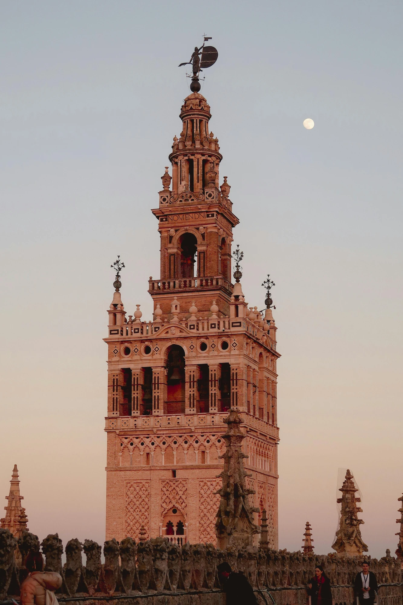 Seville's Giralda at sunset, with the moon in the background.