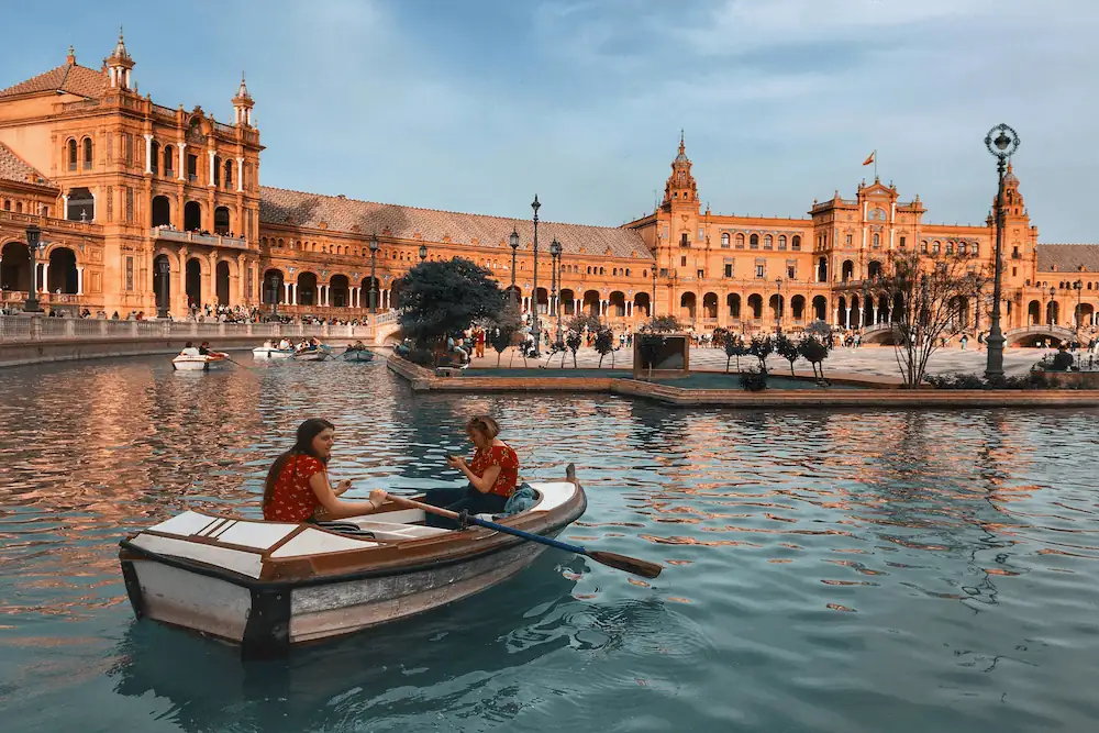 Two women in a boat on the canal of the Plaza de España in Seville, in a moment of literary reflection.